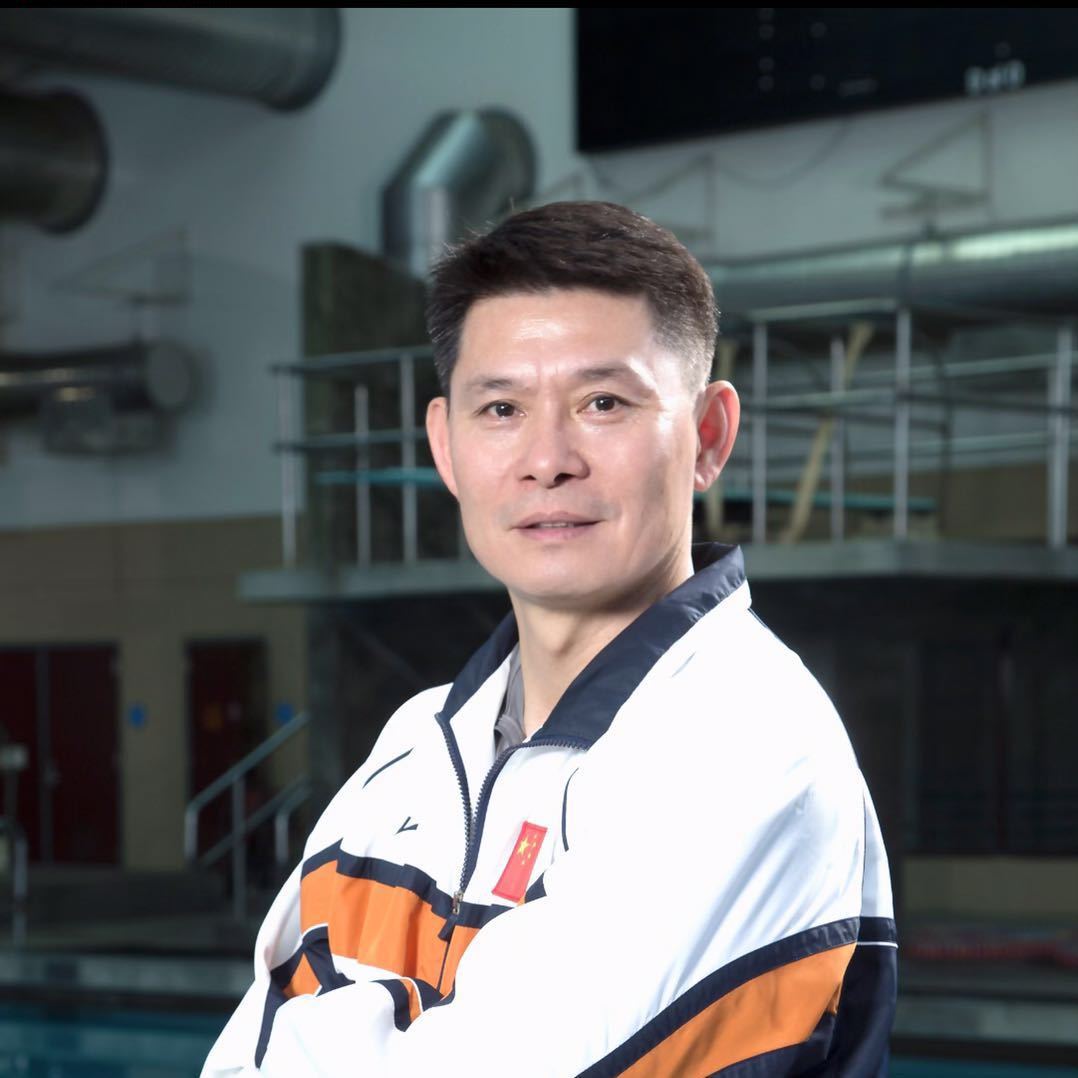 Coach Deliang Li in a national team jacket beside a diving pool