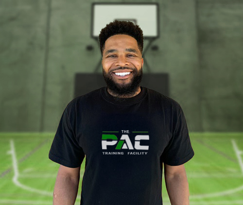 Coach Dominic Priestley standing on a basketball court in a PAC Training Facility shirt