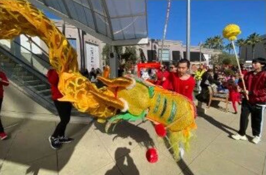 Students performing a golden dragon dance at a shopping plaza event