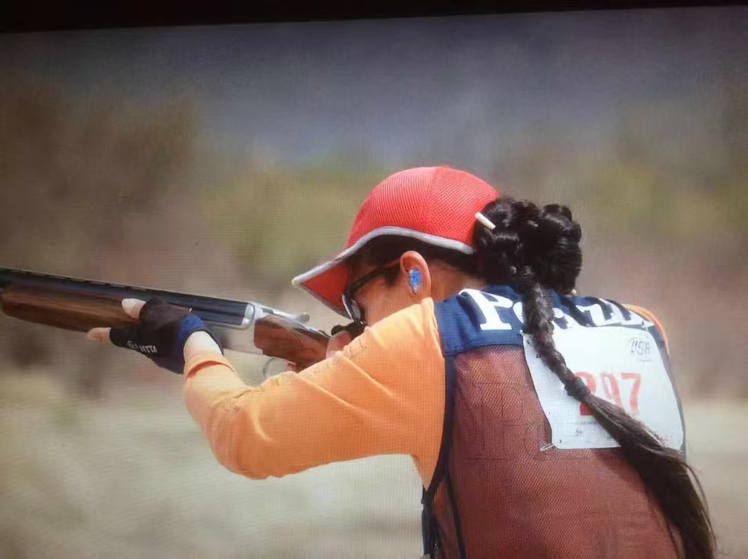 Coach Jane Pingping Ye aiming a shotgun during a trap and skeet competition