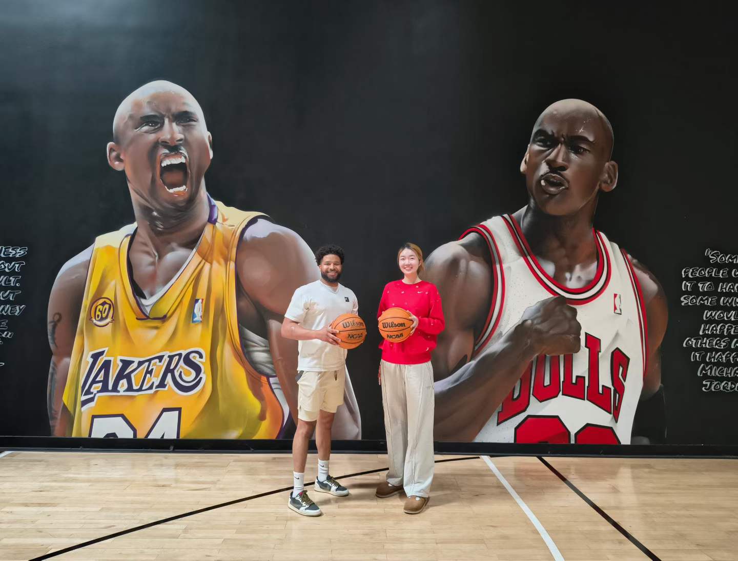 Coach Niu Liu holding a basketball in front of a basketball mural